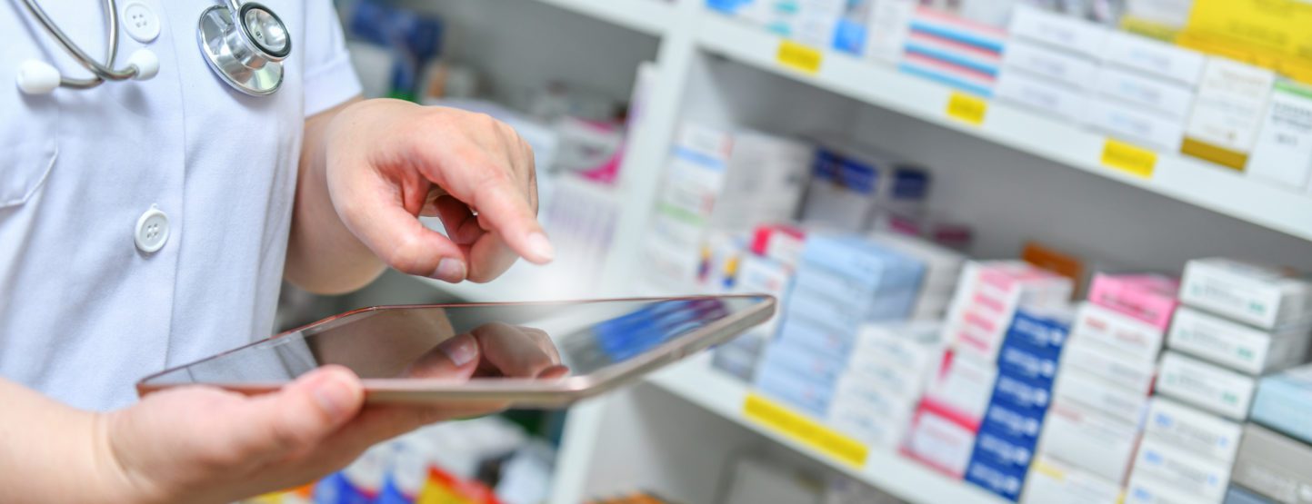 Pharmacist using an iPad to look up patient prescription