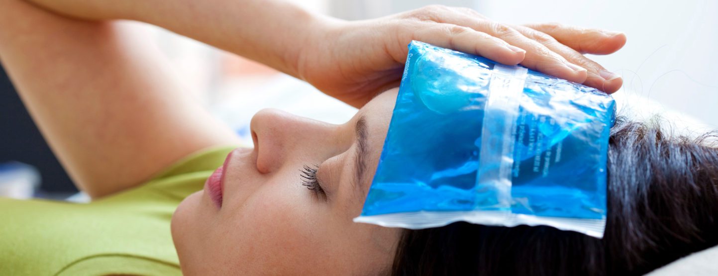 Woman lying down with gel ice pack on forehead